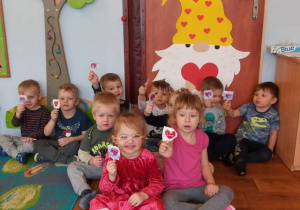 Dzieci siedzą i trzymają w rączkach lizaki w kształcie serca